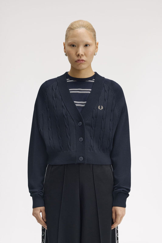 Person wearing a navy cardigan over a striped shirt with a visible brand logo on a white background