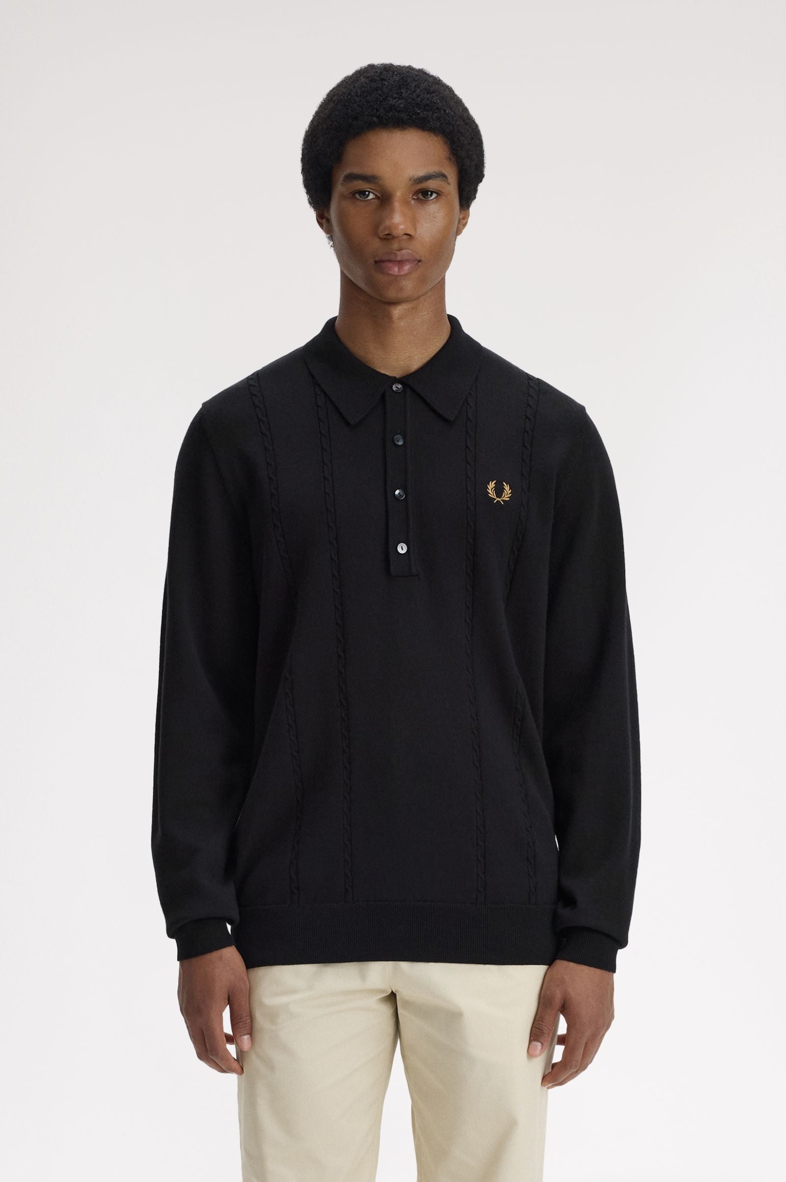 Person wearing a black long-sleeve polo shirt with a brand logo on a white background