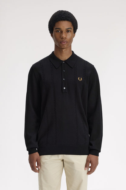Person wearing a black long-sleeve polo shirt with a brand logo on a white background