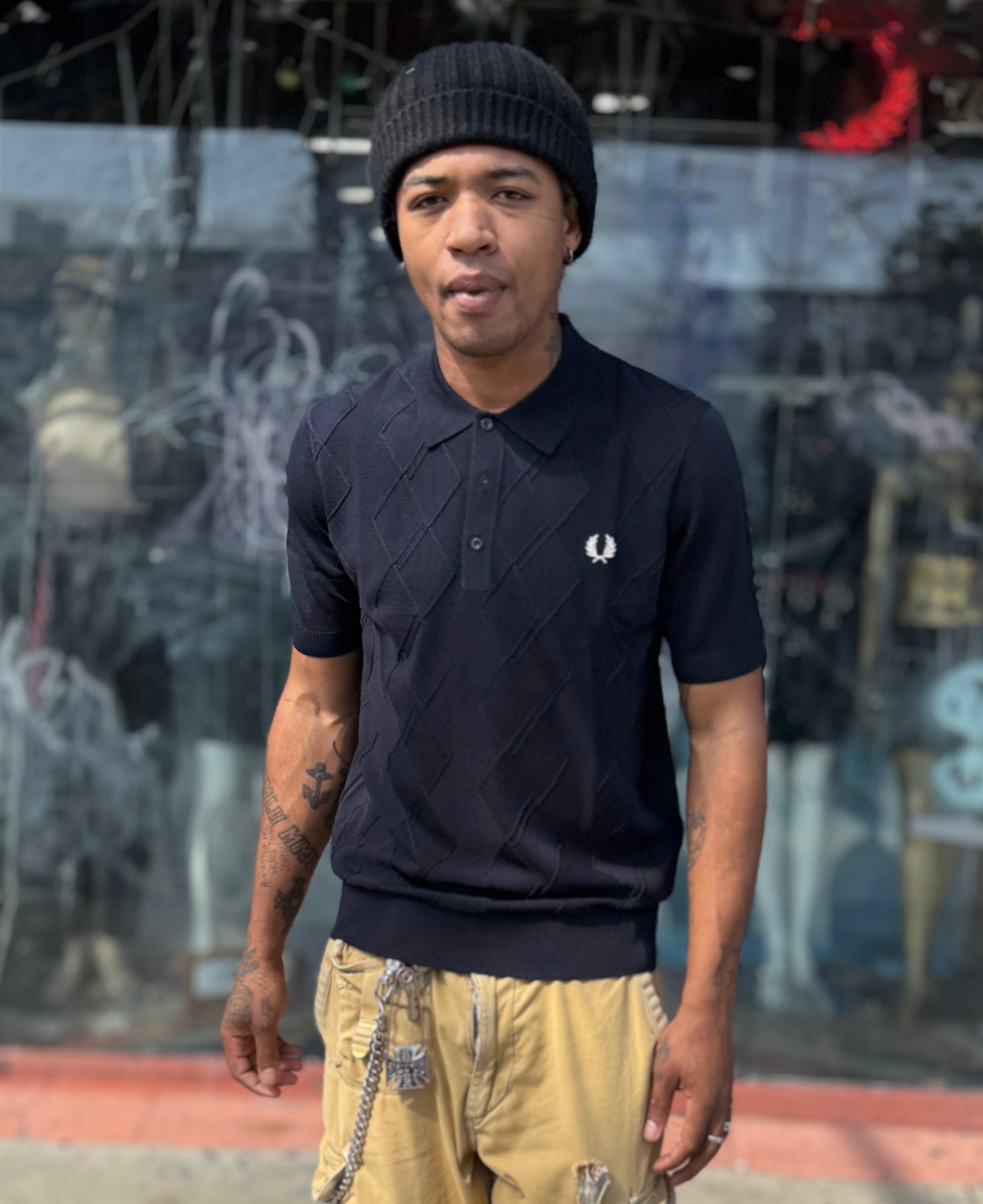 A person wearing a navy cable knitted shirt and a beanie hat.