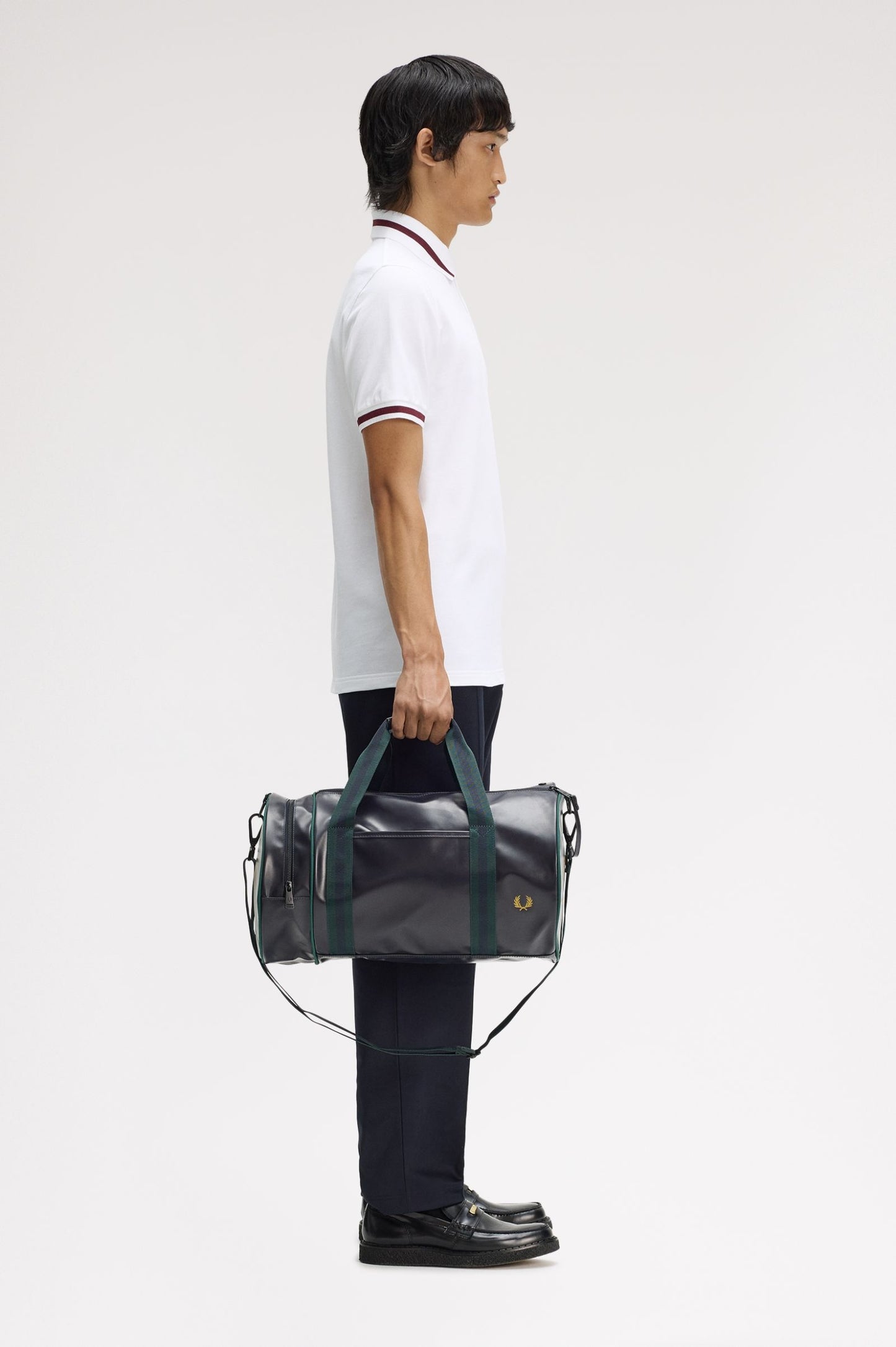 Person holding a black duffel bag with green handles against a white background