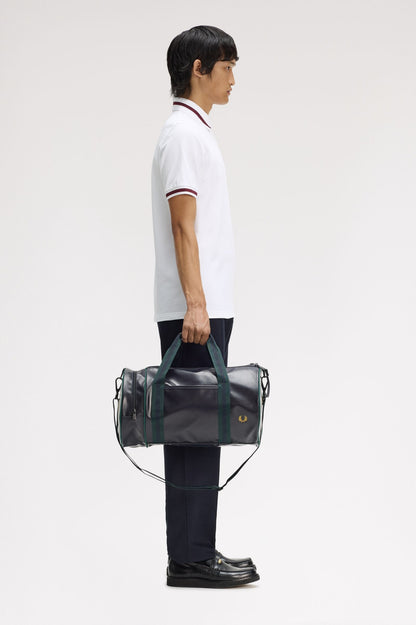 Person holding a black duffel bag with green handles against a white background