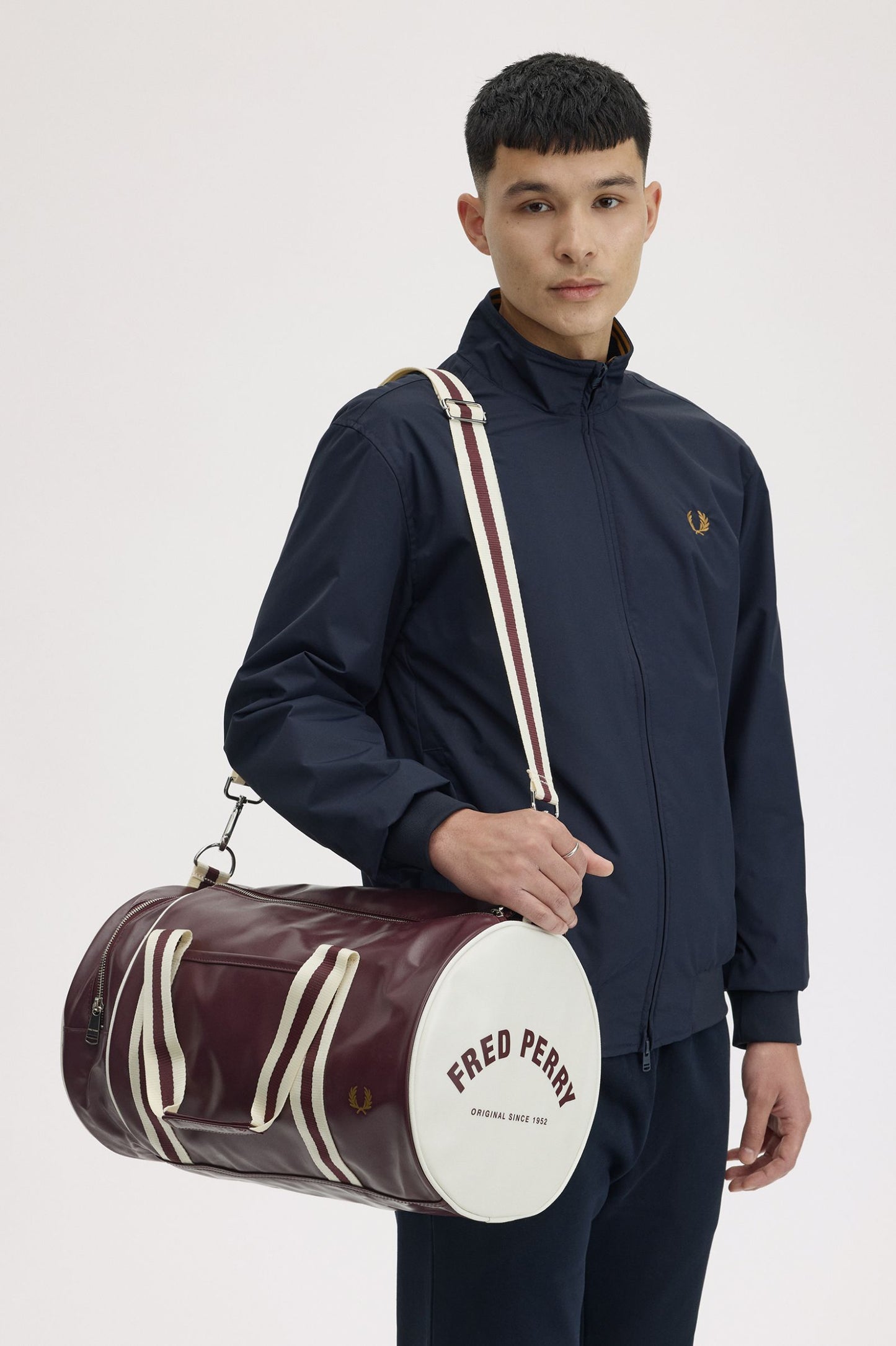 Man holding a Fred Perry duffel bag against a white background