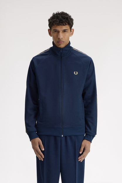 Man wearing a navy tracksuit with a brand logo on a white background