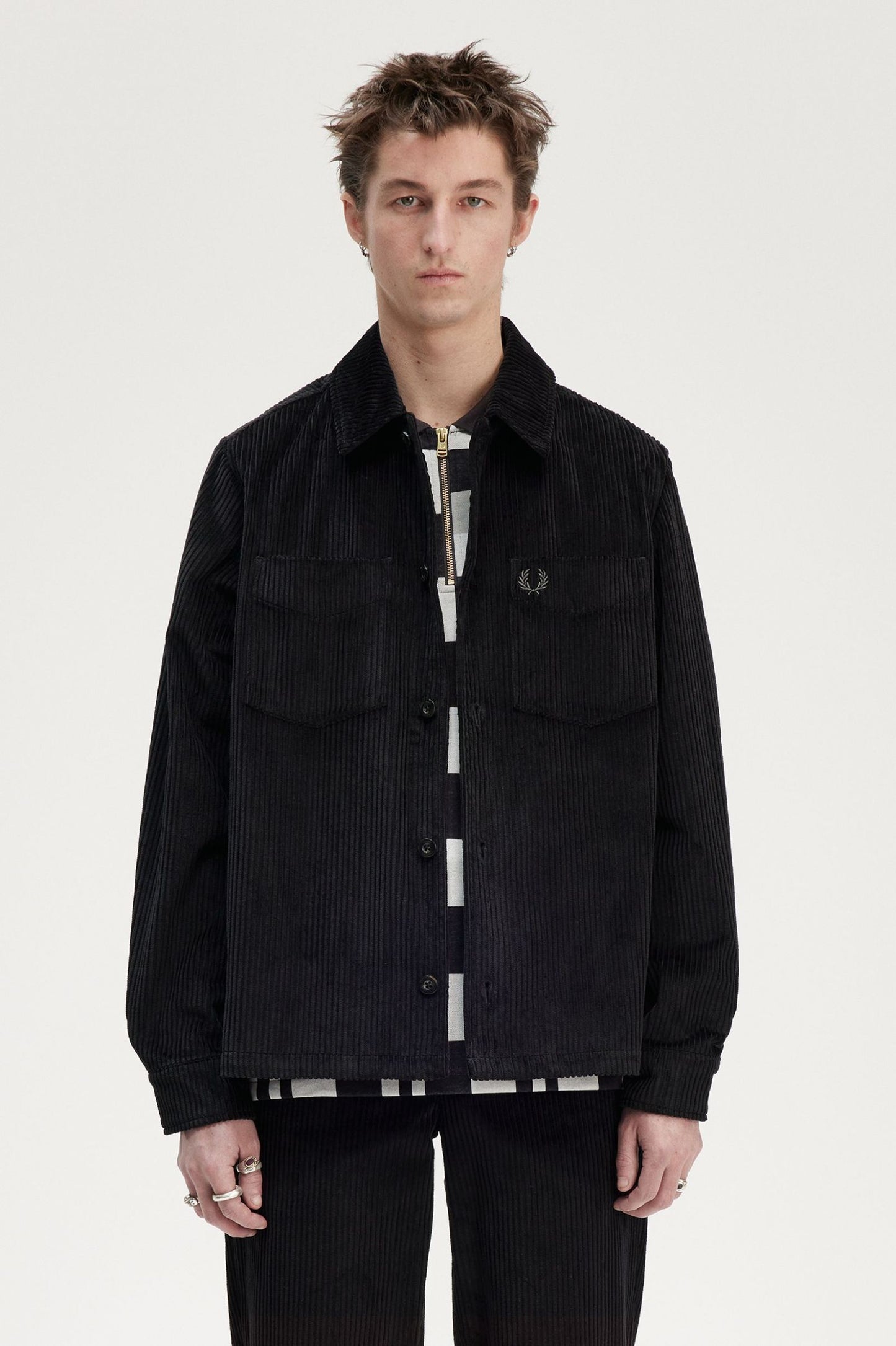 A male model wearing a black Fred Perry Corduroy Overshirt with a collared neckline and long sleeves.