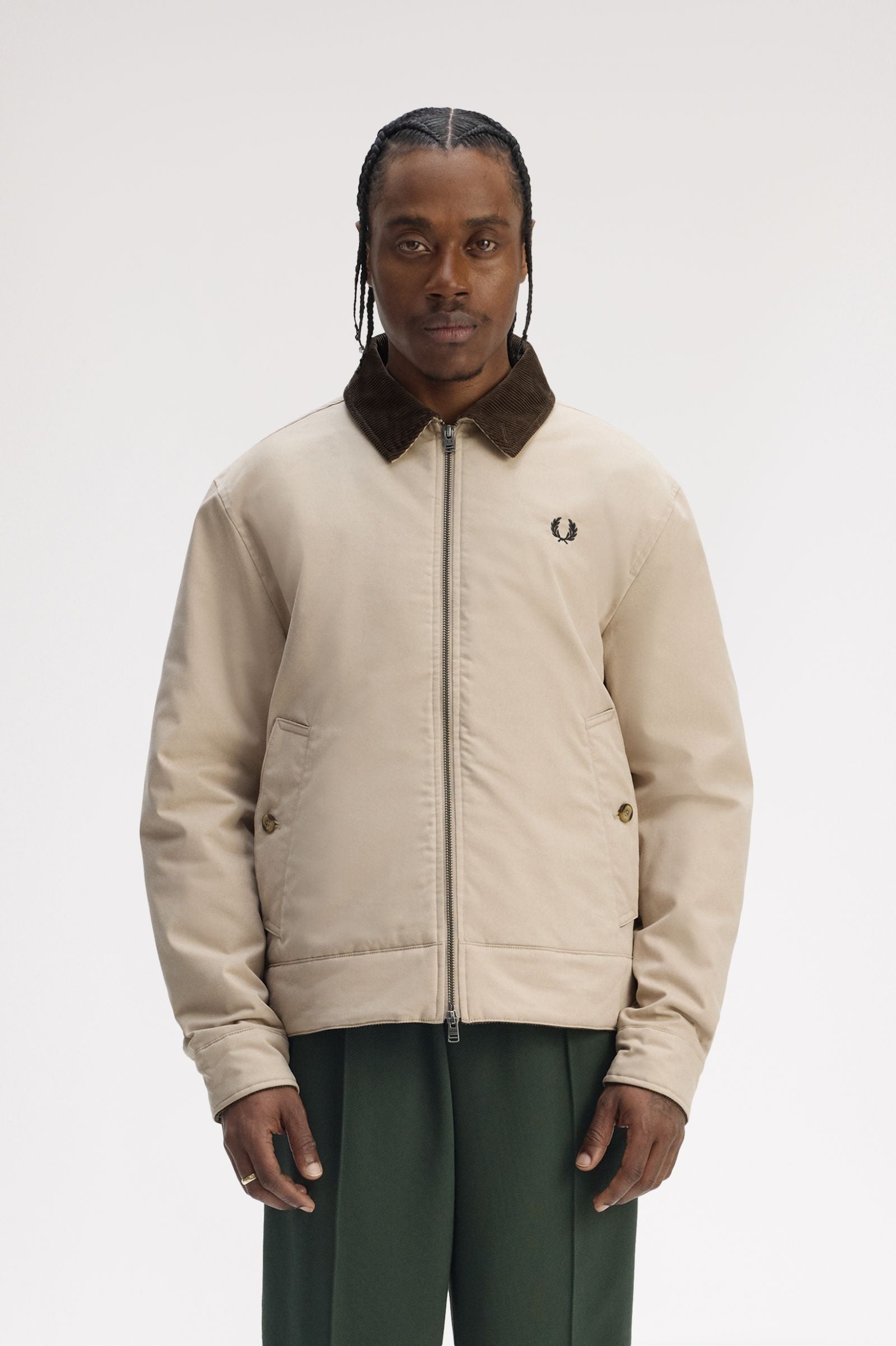 Man wearing a beige jacket with a brand logo on a white background