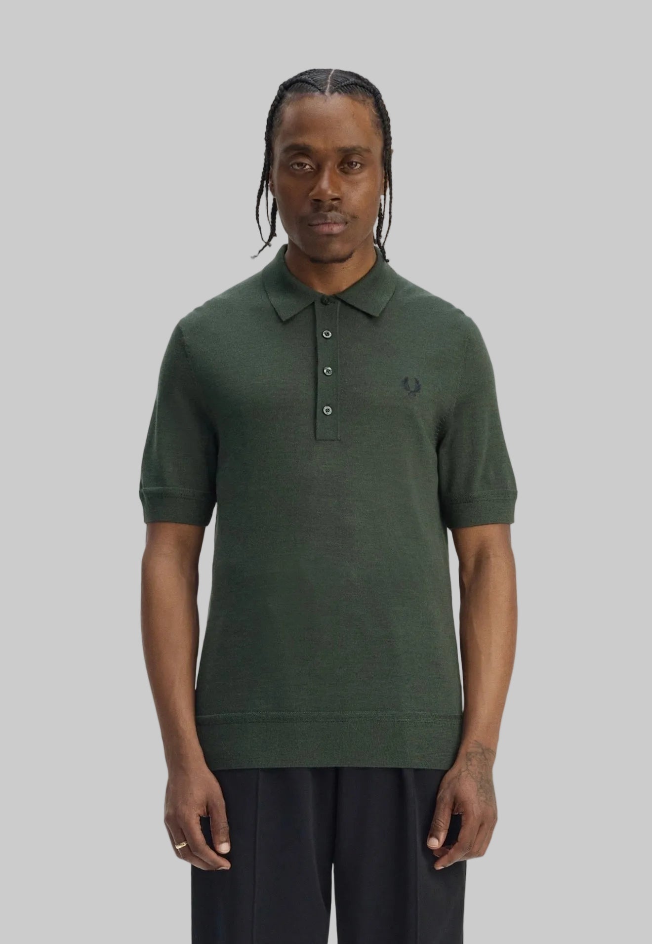 Man wearing a green polo shirt with a brand logo on a white background