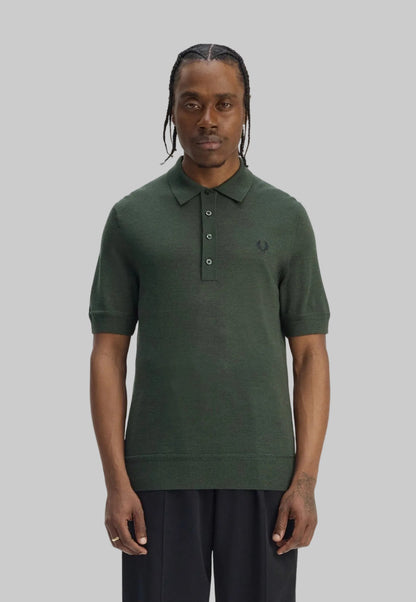 Man wearing a green polo shirt with a brand logo on a white background