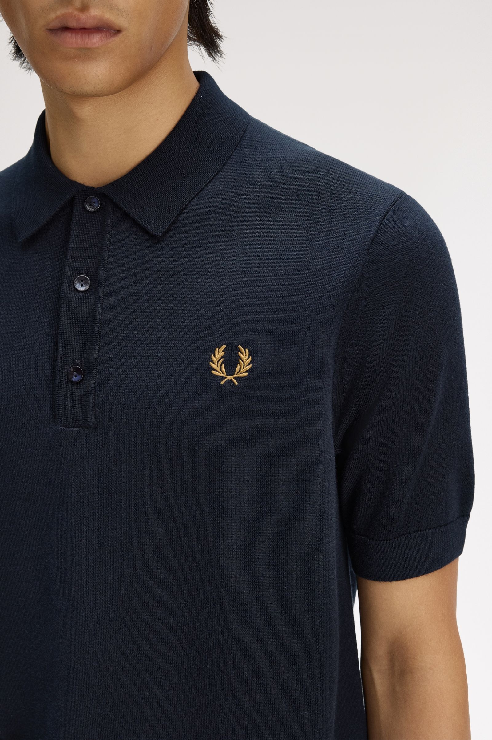 Navy polo shirt with a gold logo on a white background