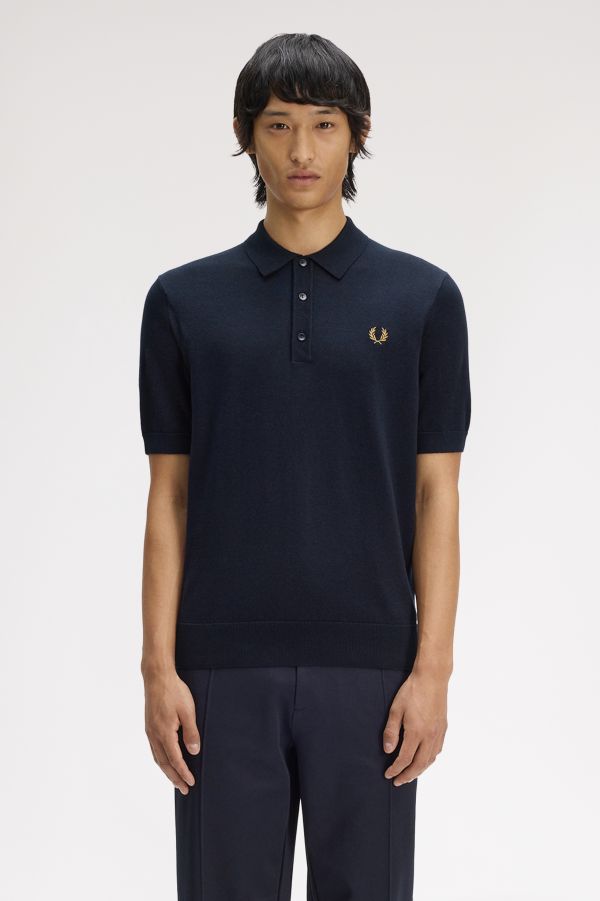 Person wearing a navy polo shirt with a brand logo on a white background