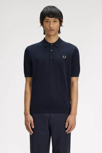 Person wearing a navy polo shirt with a brand logo on a white background