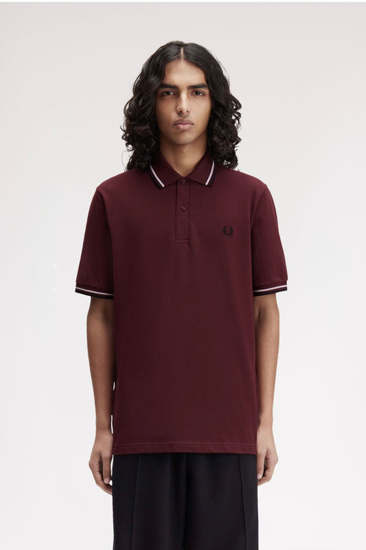 Person wearing a maroon polo shirt with a brand logo on a plain background