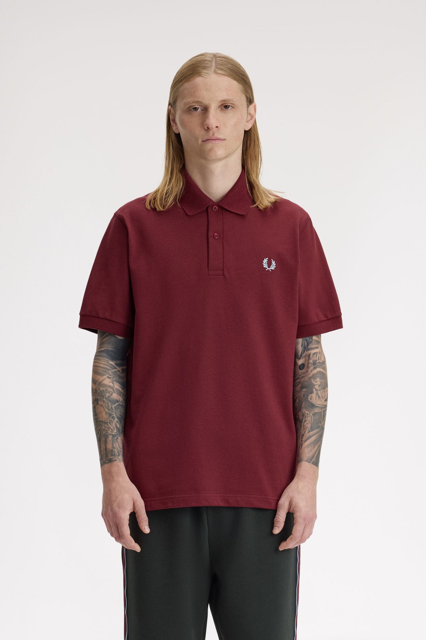 Person wearing a maroon polo shirt with a brand logo on a white background