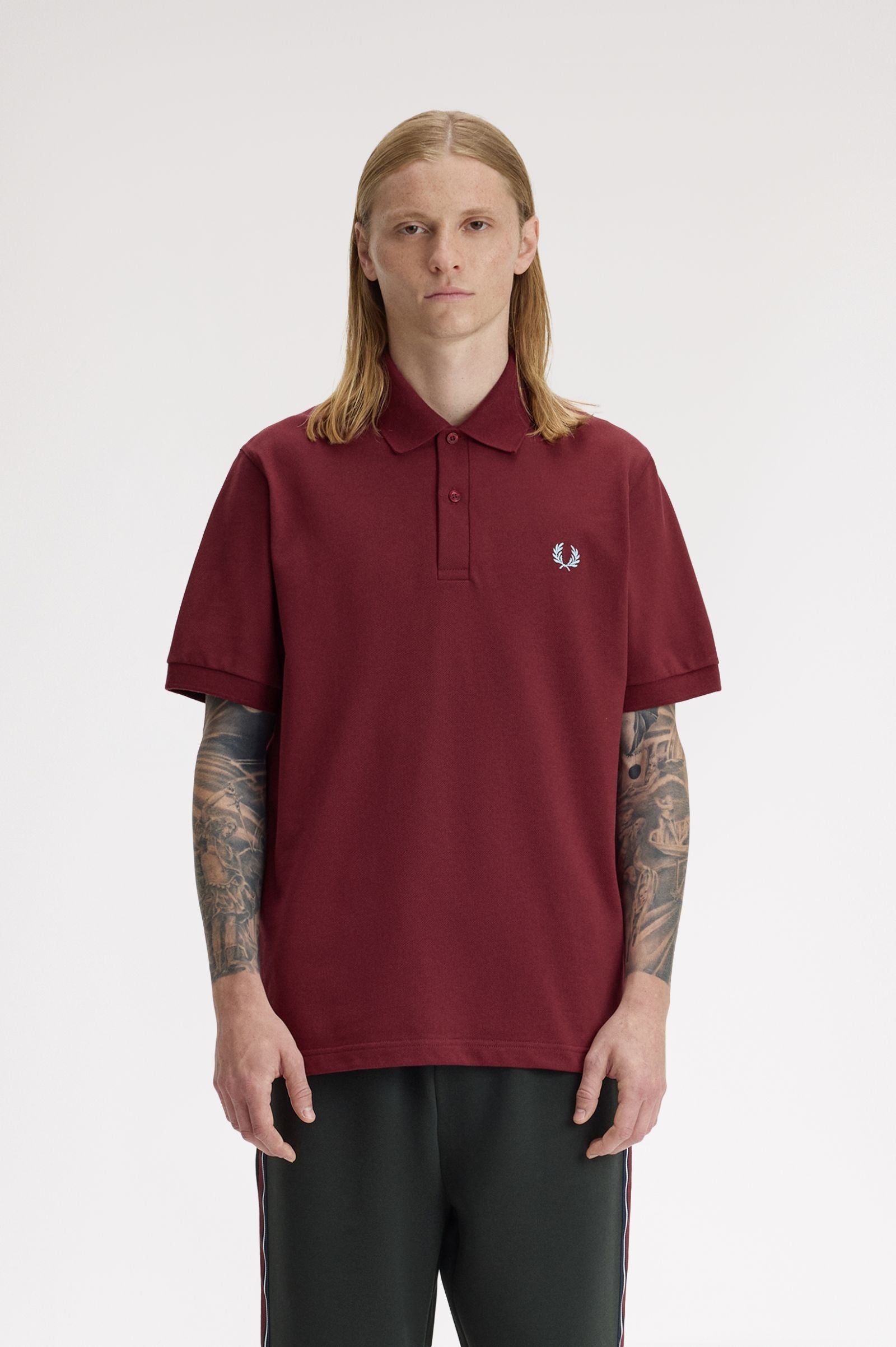 Person wearing a maroon polo shirt with a brand logo on a white background