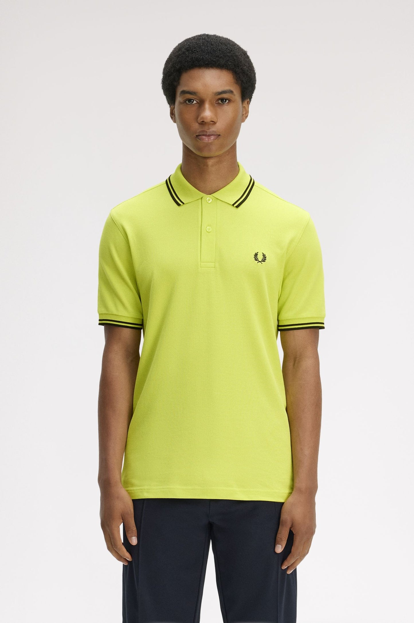Person wearing a bright yellow polo shirt with black trim on a white background