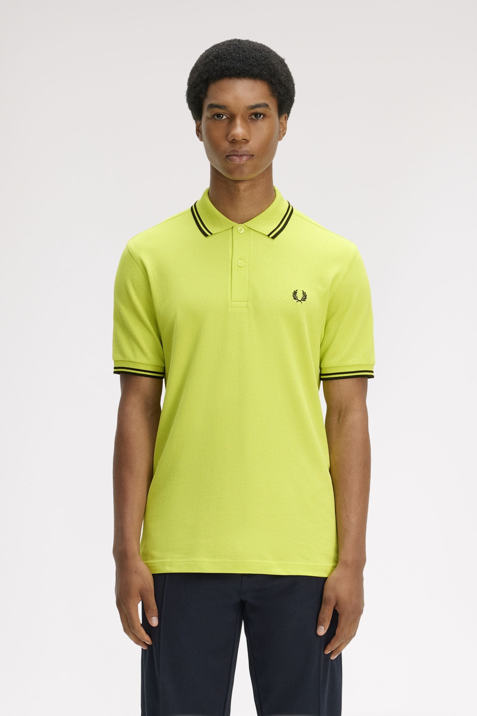 Person wearing a bright yellow polo shirt with black trim on a white background