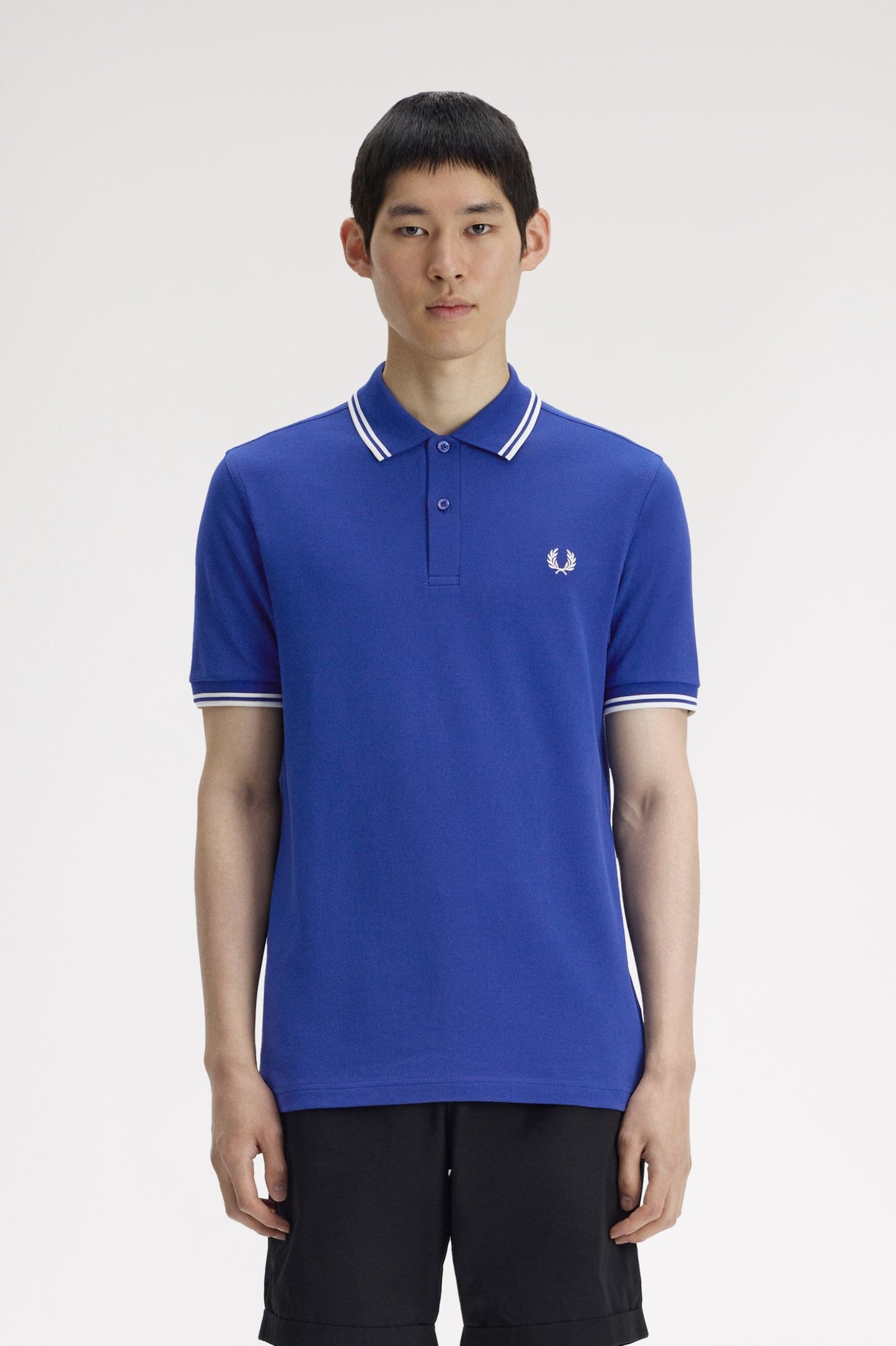 Person wearing a blue polo shirt with a brand logo on a white background
