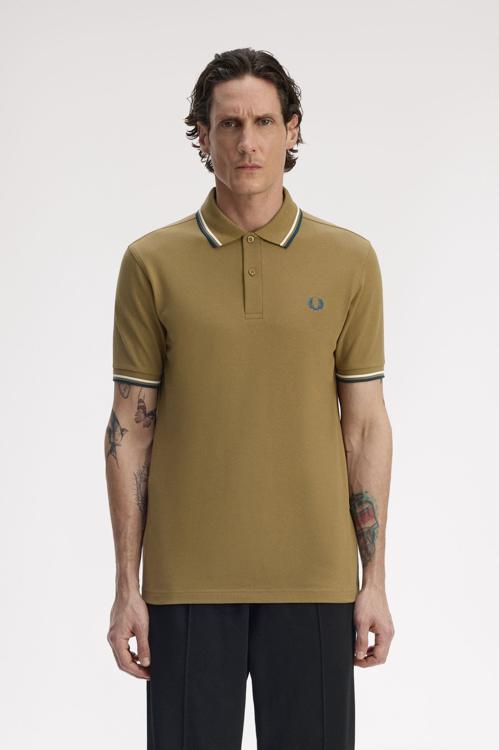 Man wearing a brown polo shirt with a brand logo on a white background
