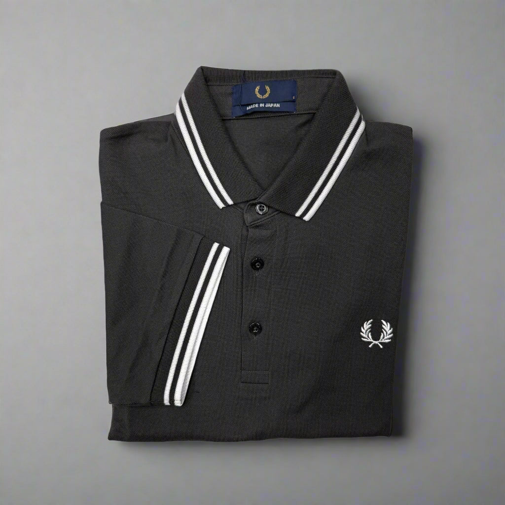 Folded black polo shirt with white trim and brand logo on a white background