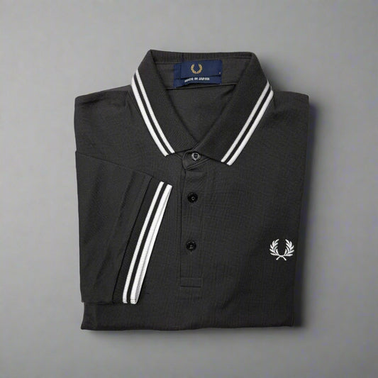 Folded black polo shirt with white trim and brand logo on a white background