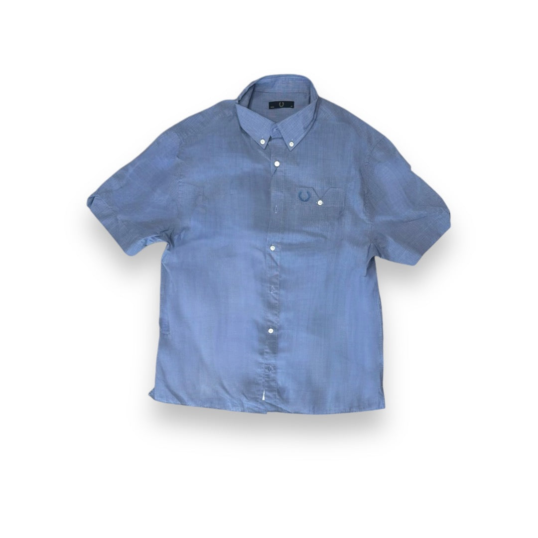 A blue Fred Perry notch pocket shirt with a collar, buttons down the front, and a notch pocket on the left side.