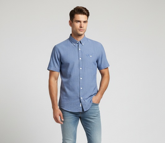 Man wearing a blue shirt and jeans on a light gray background