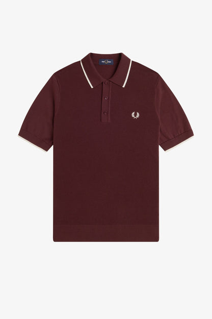 Maroon polo shirt with white trim on a light gray background