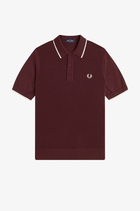 Maroon polo shirt with white trim on a light gray background