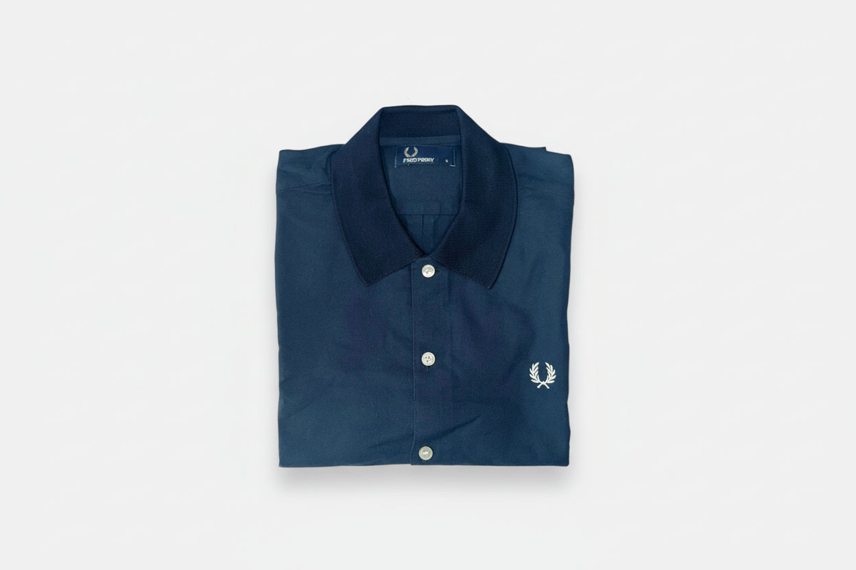 A navy blue Fred Perry polo shirt with a knitted collar, displayed on a white background.