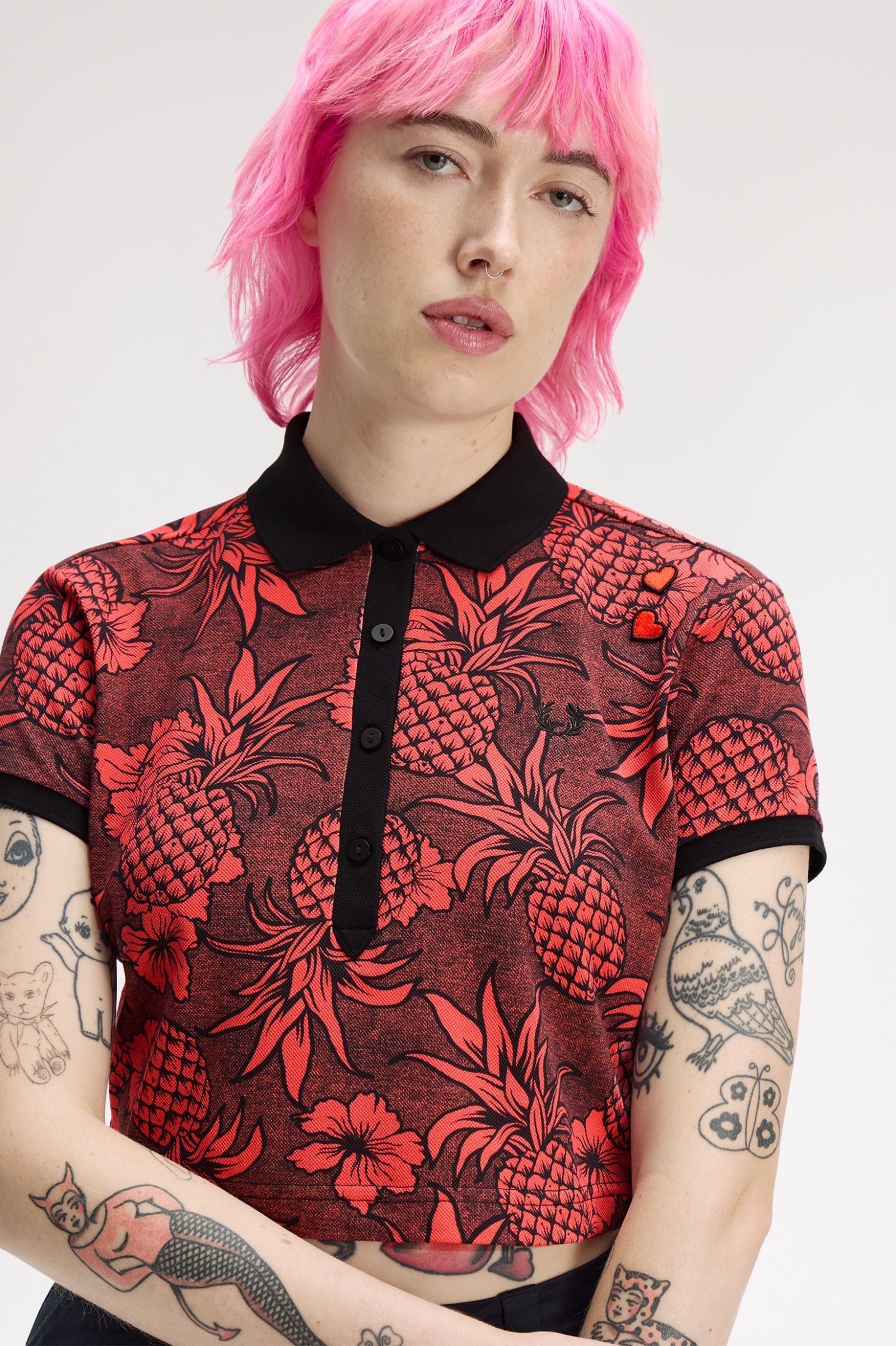 Person wearing a red and black patterned shirt with pink hair on a white background