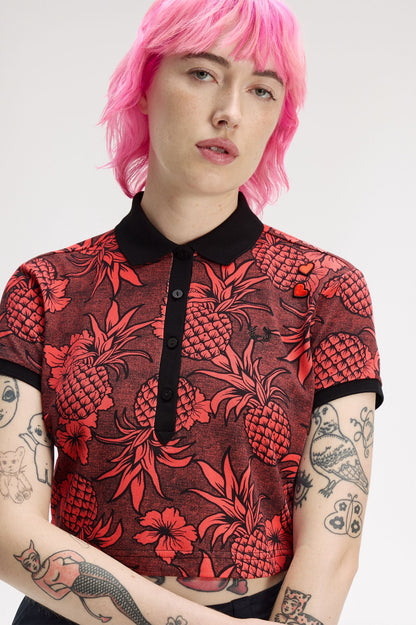 Person wearing a red and black patterned shirt with pink hair on a white background