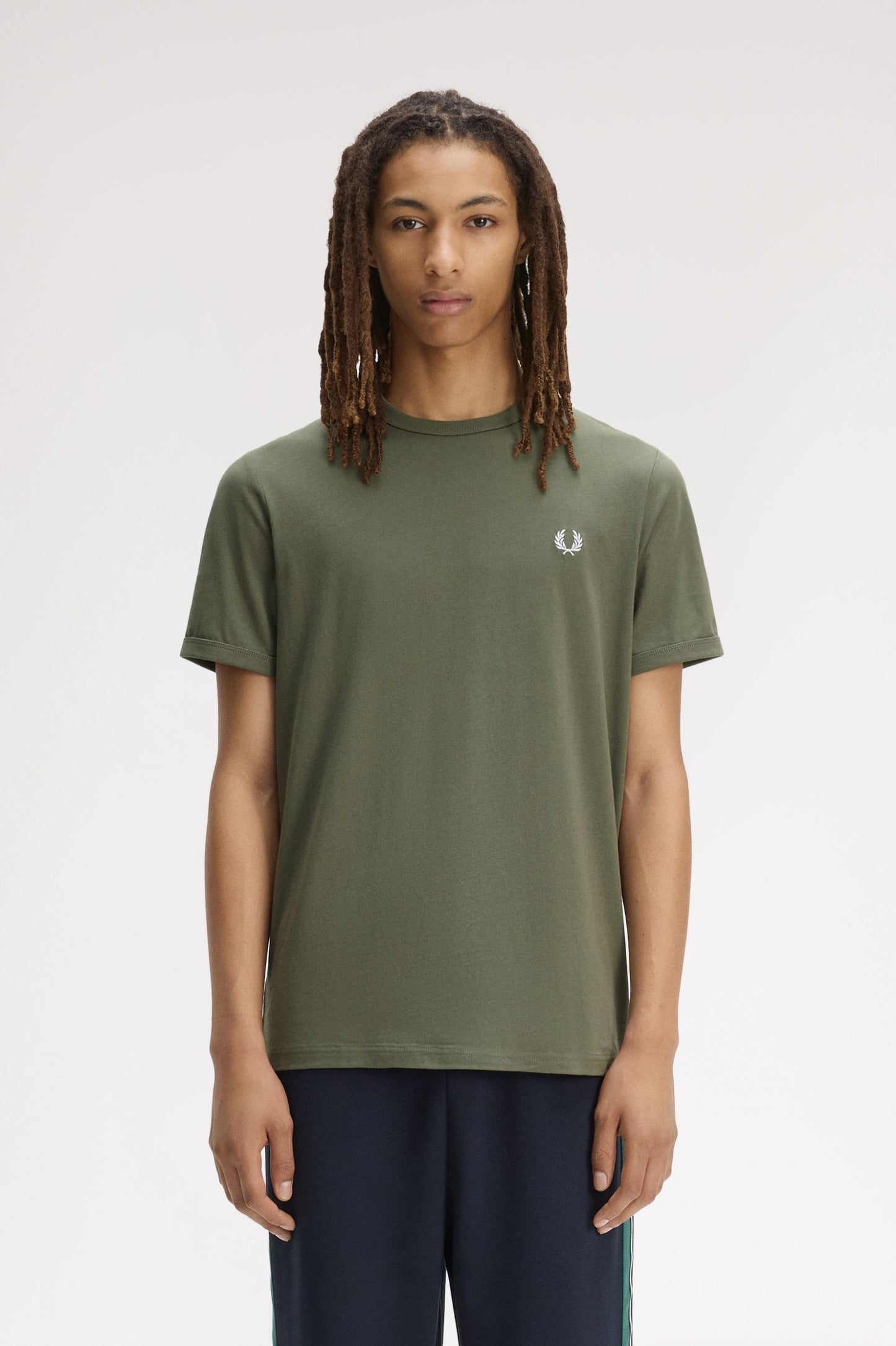 Person wearing a green t-shirt with a brand logo on a white background