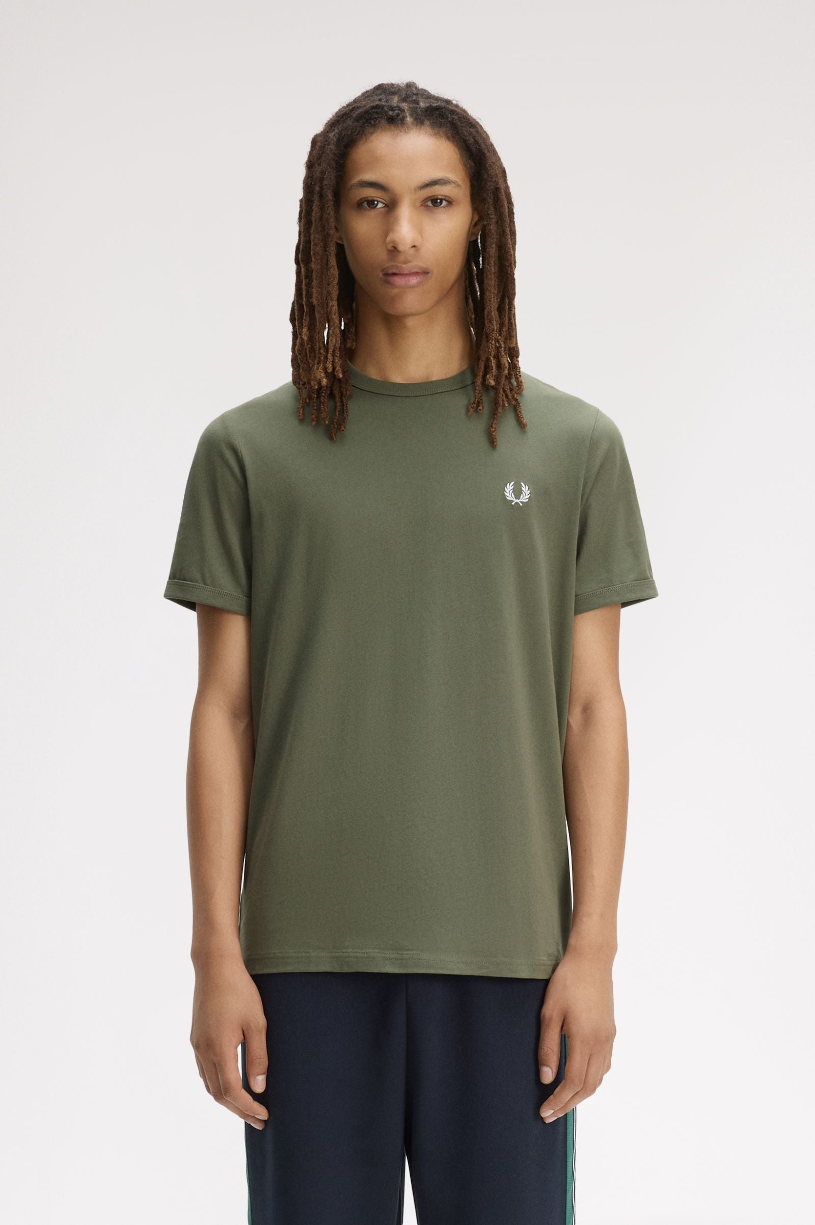 Person wearing a green t-shirt with a brand logo on a white background