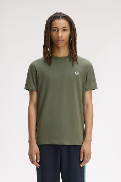 Person wearing a green t-shirt with a brand logo on a white background