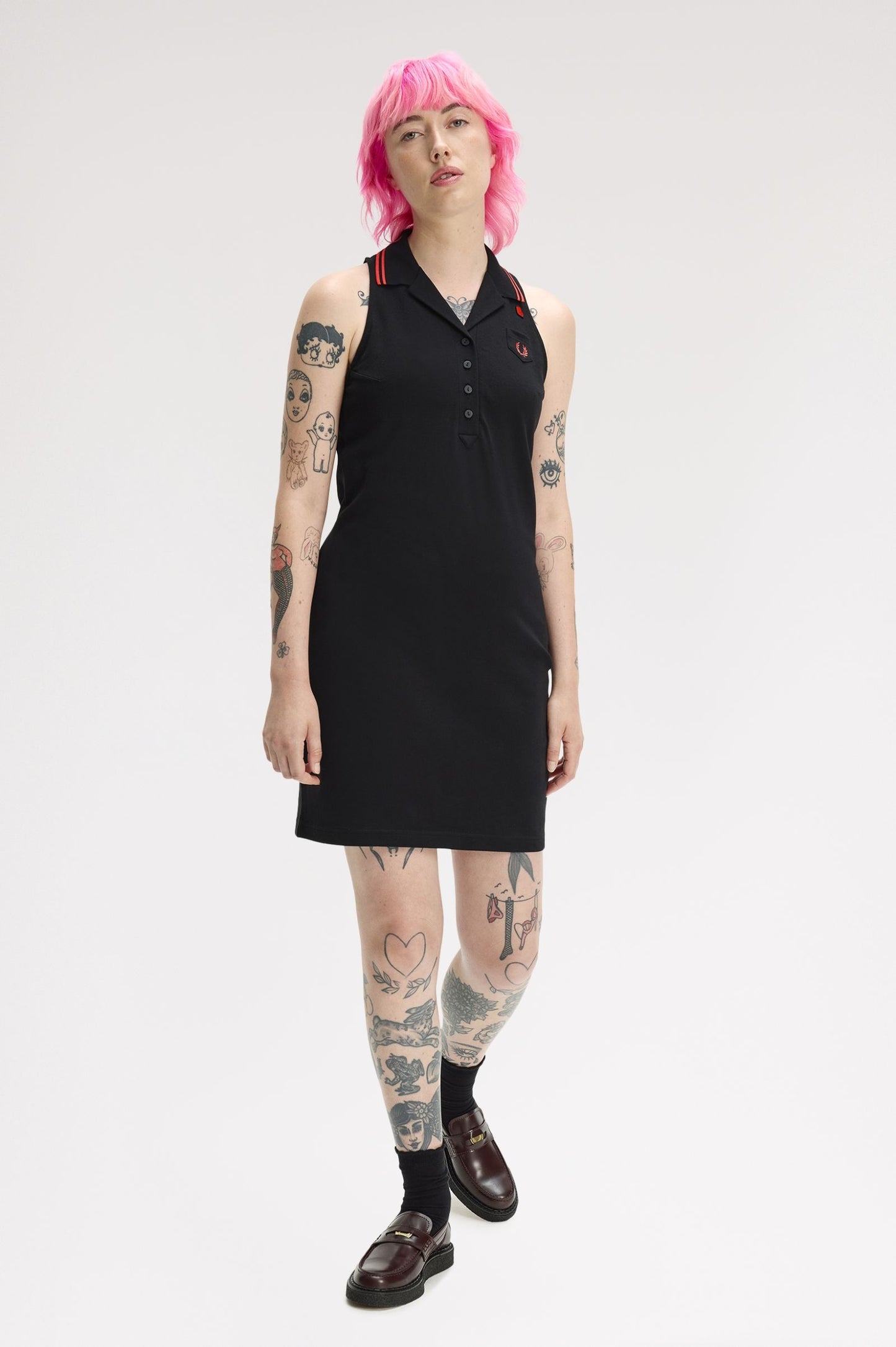 Person wearing a black sleeveless dress with red accents on a white background