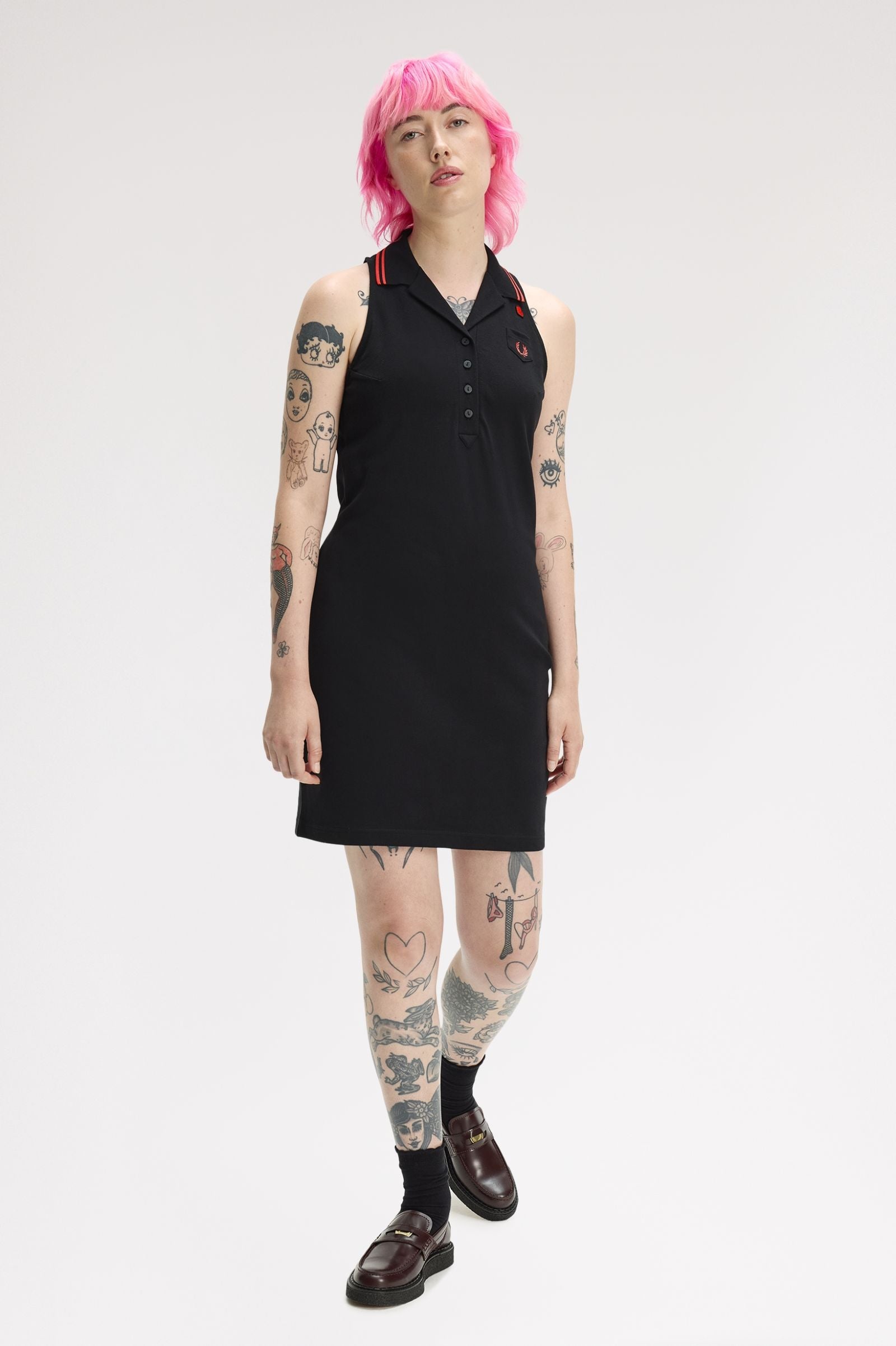 Person wearing a black sleeveless dress with red accents on a white background