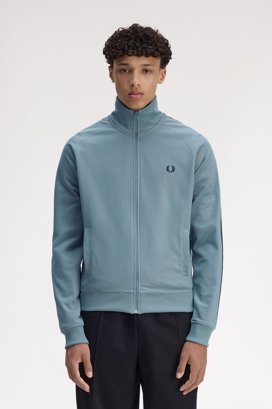 Person wearing a light blue tracksuit with a brand logo on a white background