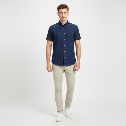 Man wearing a navy checkered shirt and beige pants on a white background