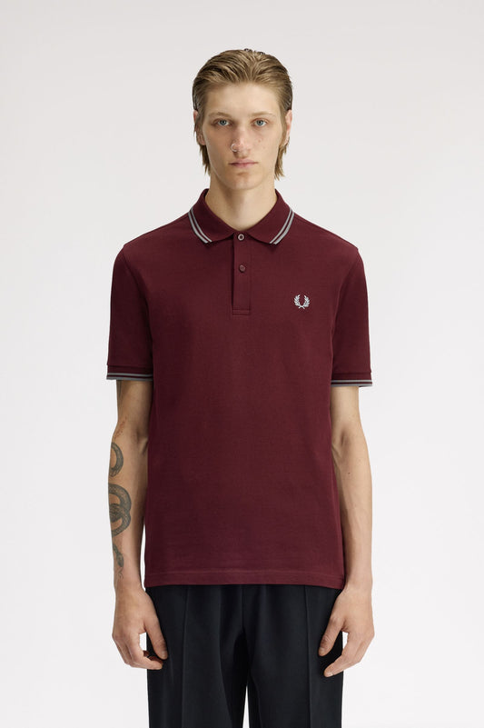 Person wearing a maroon polo shirt with a brand logo on a white background