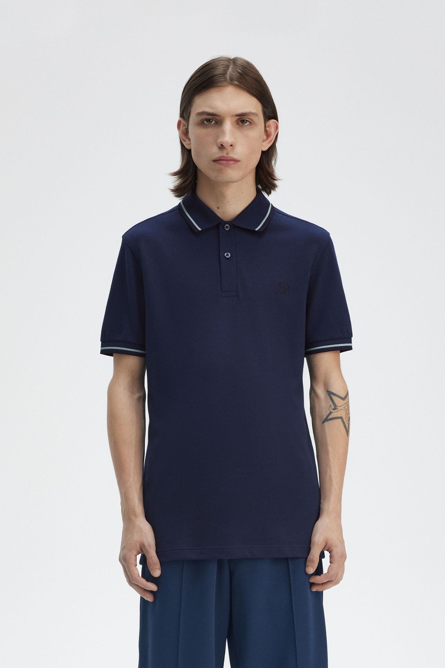 Person wearing a navy blue polo shirt with white trim on a light gray background