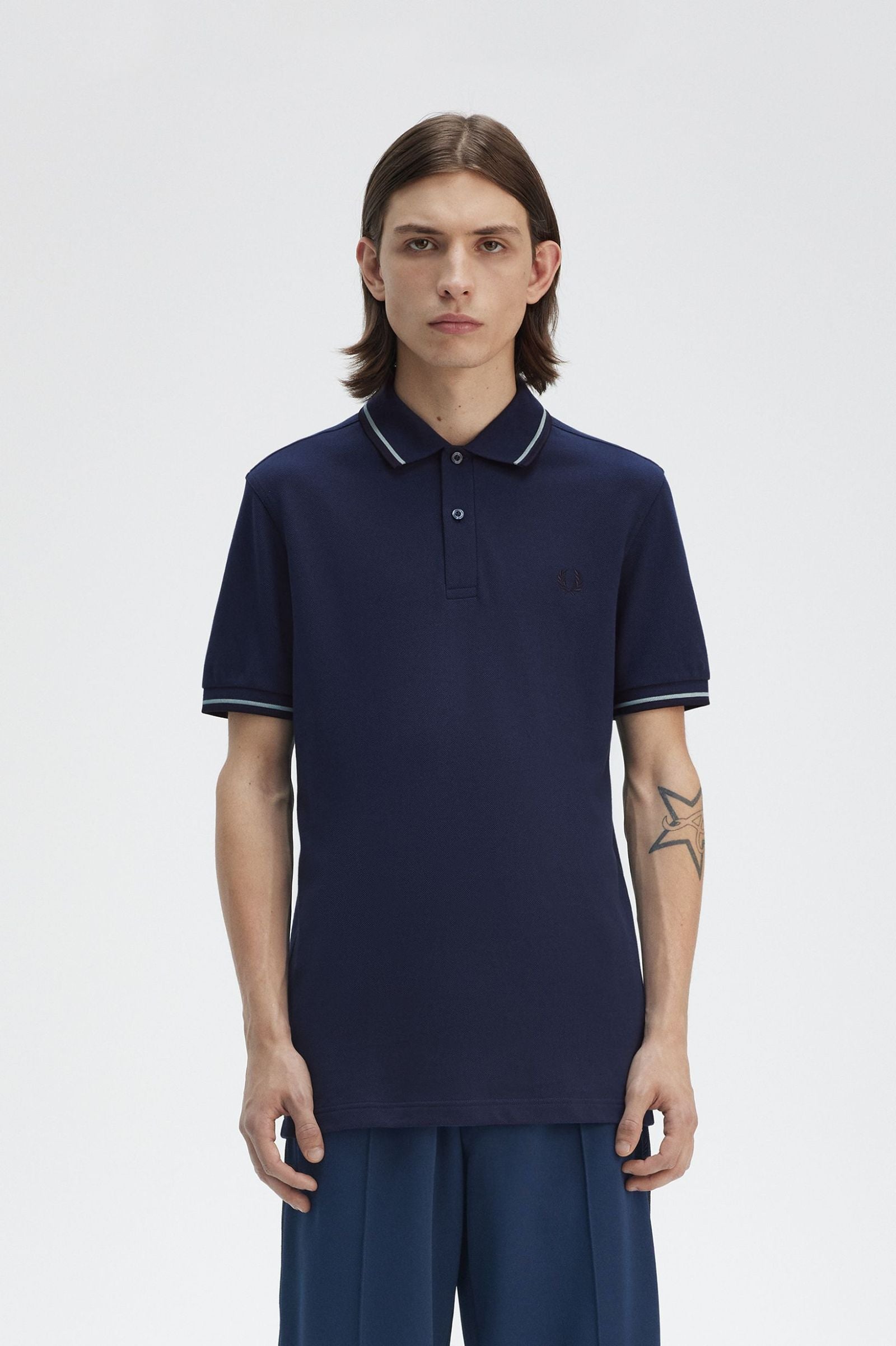 Person wearing a navy blue polo shirt with white trim on a light gray background
