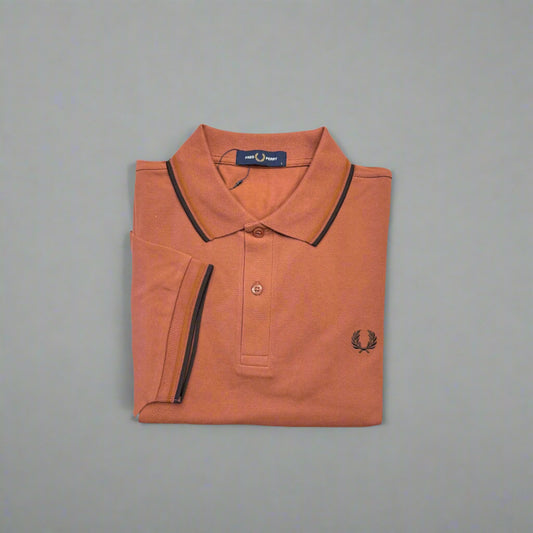 Folded orange polo shirt with black trim on a white background