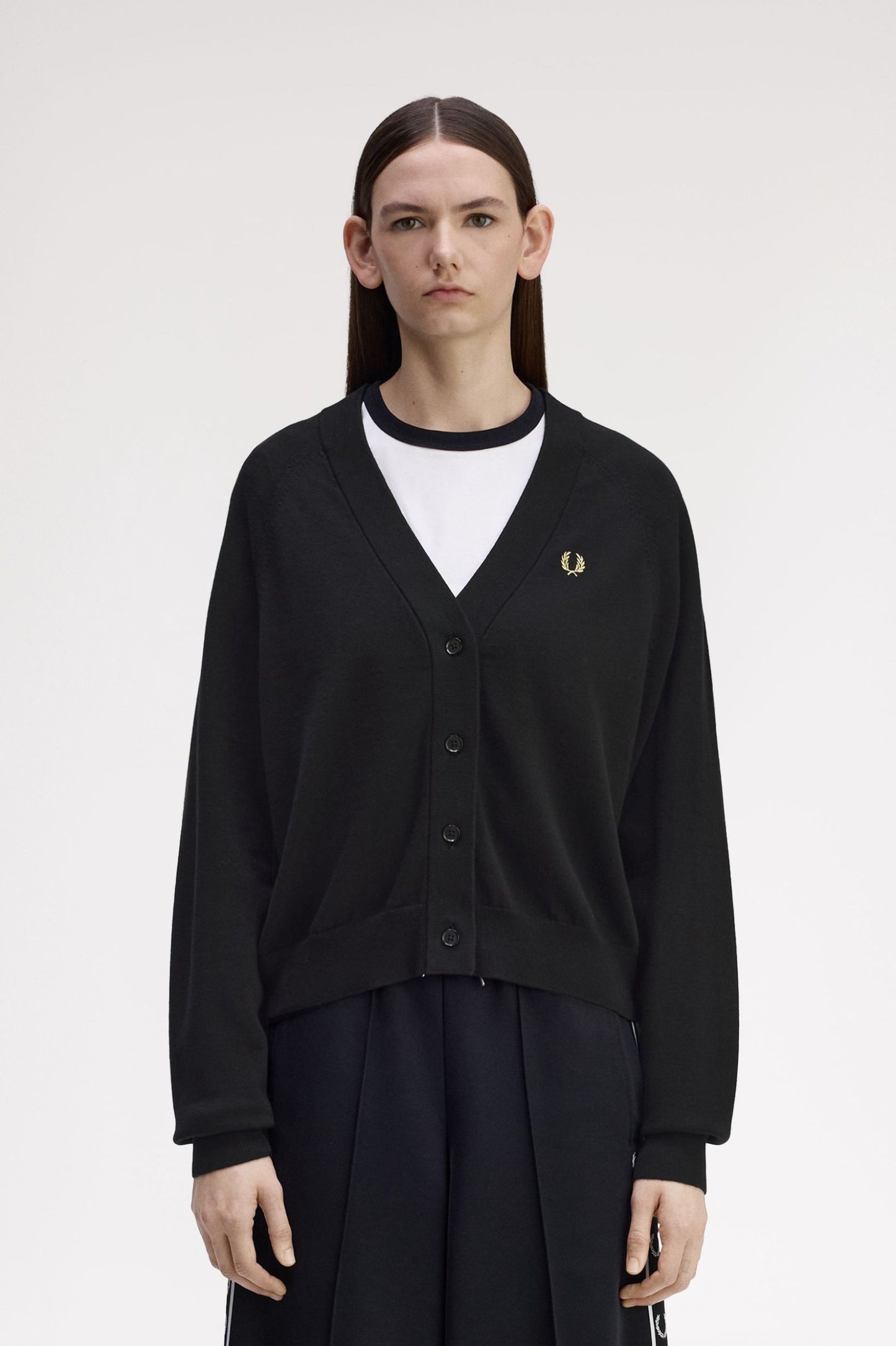 Person wearing a black cardigan with a brand logo on a white background