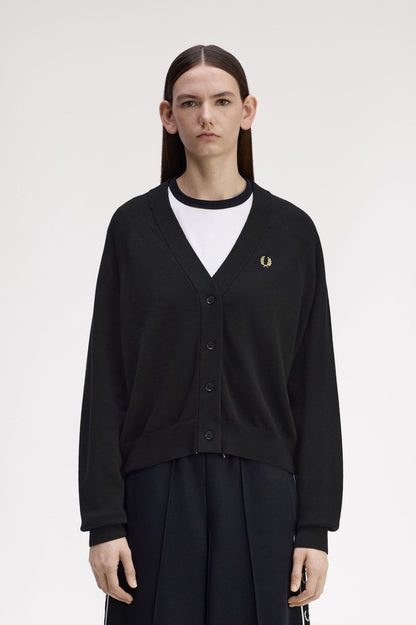 Person wearing a black cardigan with a brand logo on a white background