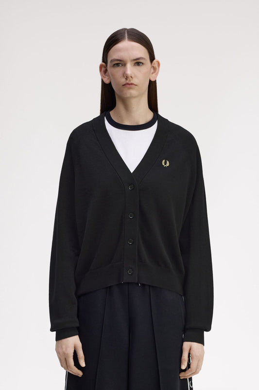 Person wearing a black cardigan with a brand logo on a white background