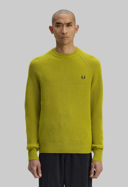 Man wearing a green sweater with a brand logo on a white background