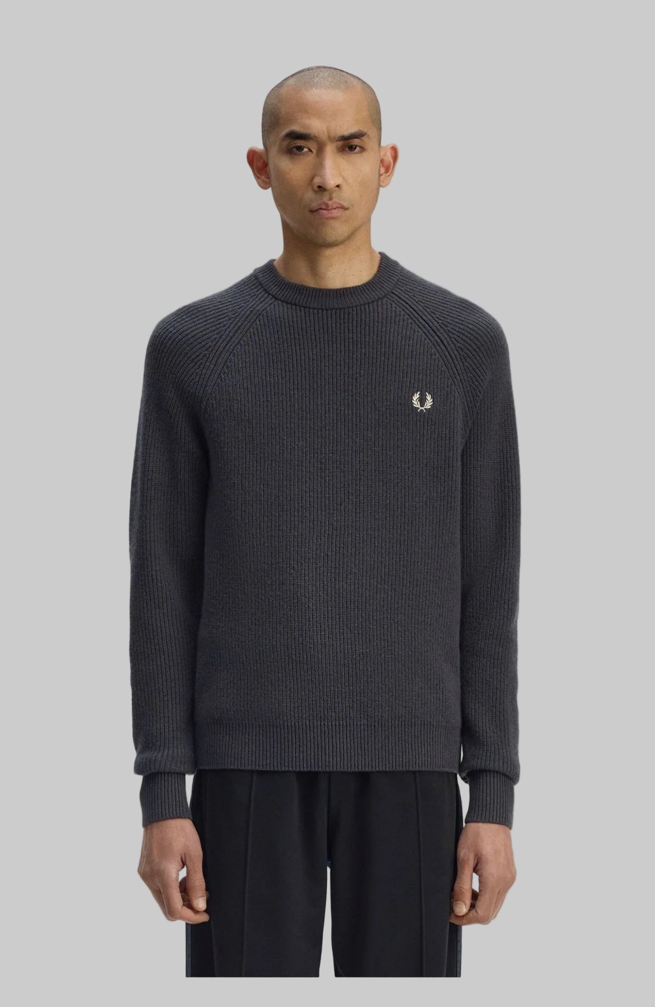 Man wearing a dark gray sweater with a brand logo on a white background