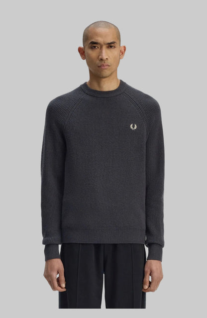 Man wearing a dark gray sweater with a brand logo on a white background