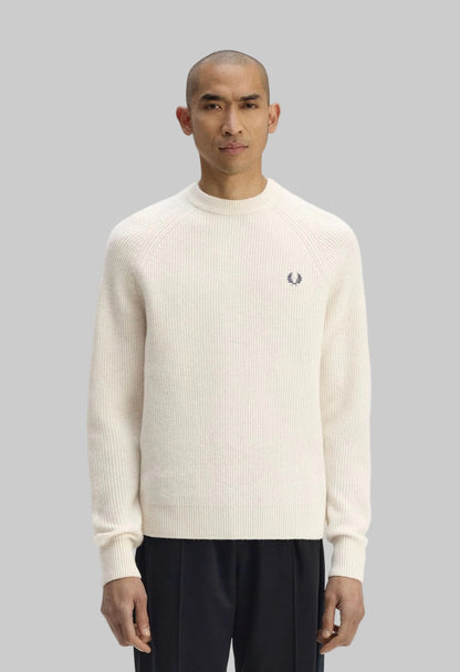 Man wearing a cream sweater with a brand logo on a white background