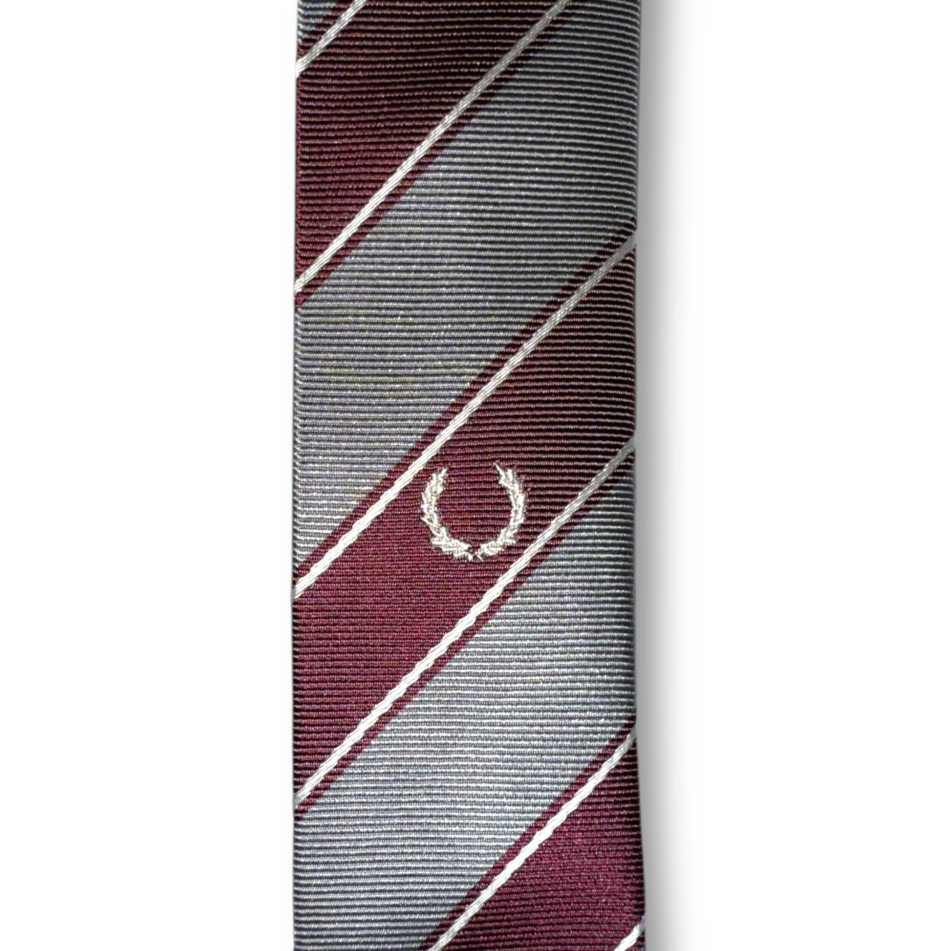A striped necktie with a combination of dark and light colors, featuring a small logo at the tip.